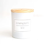 A white cylindrical candle with a wooden lid, labeled 'LUMINOUS' and 'ORGANIC'.