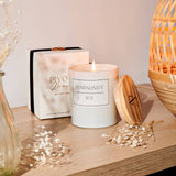 Candle with 'Luminosity' packaging on a wooden surface with decorative elements.