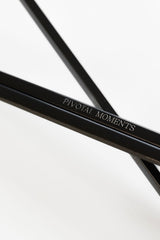 Close-up of a black candle trimmer frame with 'Pivotal Moments' engraving on a white background