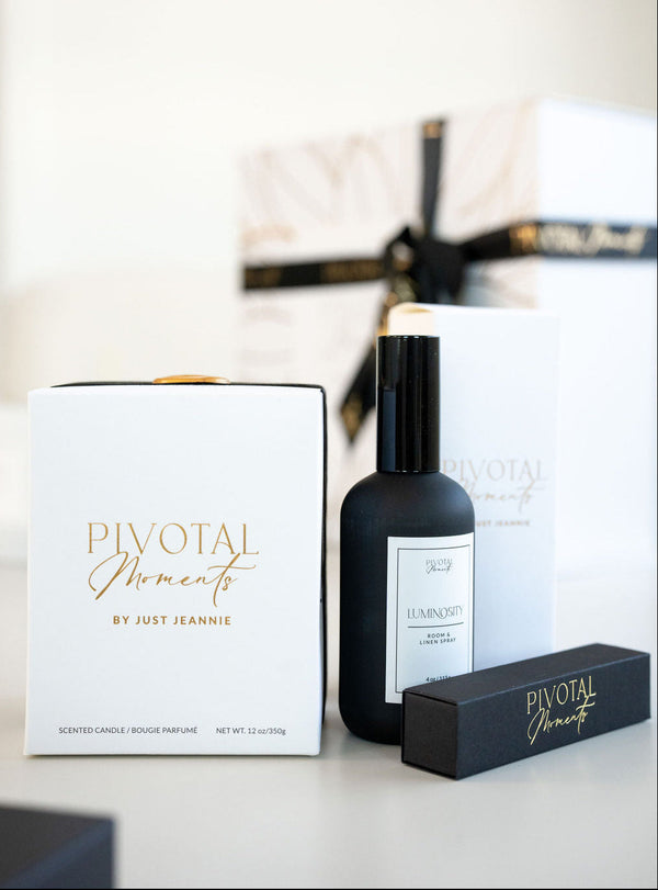 Pivotal Moments by Just Jeannie candle, perfume bottle, and packaging on a light surface.