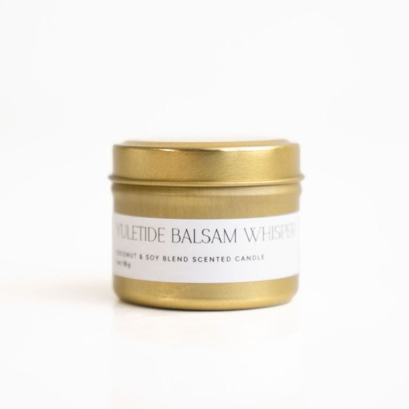 A gold tin candle with a gold-colored lid, featuring the brand logo 'PM' on the front.
