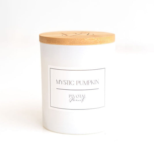 A white candle with a wooden lid, labeled 'MYSTIC PUMPKIN', set against a white background.