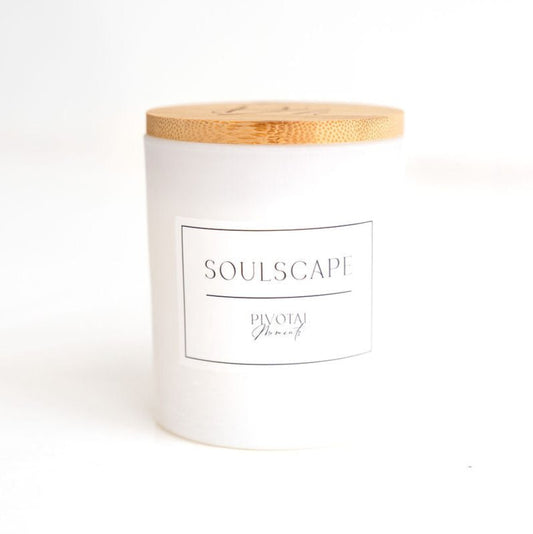 A white cylindrical glass candle with a wooden lid labeled 'SoulScape'.