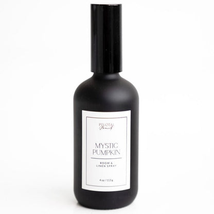 A black bottle labeled 'Mystic Pumpkin' room and linen spray by Daisies & Co. with a white label and cap.