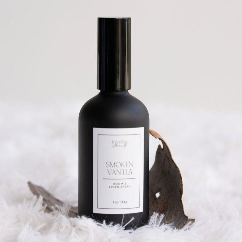 Black room spray bottle labeled 'Smoked Vanilla' on a white background with decorative elements.