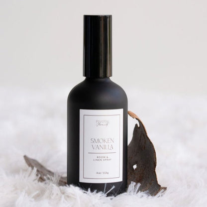 Black room spray bottle labeled 'Smoked Vanilla' on a white background with decorative elements.