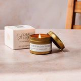 Candle with open lid on a table next to a box labeled 'Pivotal Moments' against a neutral background