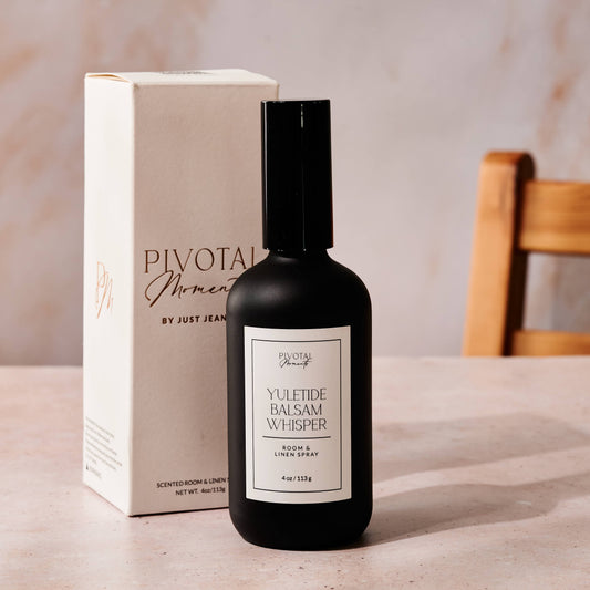 Black bottle with white label and beige box labeled 'Pivotal Moments' on a light surface.