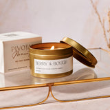 Gold candle jar with 'Berry & Bough' label on a reflective surface