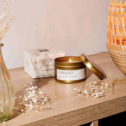 Lit candle in a decorative container on a wooden surface with a soft background