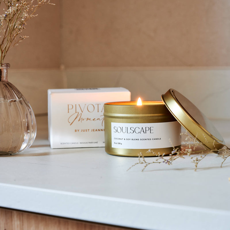 Scented candle labeled 'Soulscapes' on a surface with decorative elements.