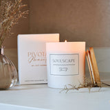 Candle labeled 'Soulscapes' on a surface with decorative elements.