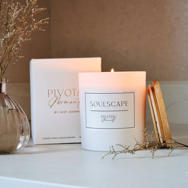 Candle labeled 'Soulscapes' on a surface with decorative elements.